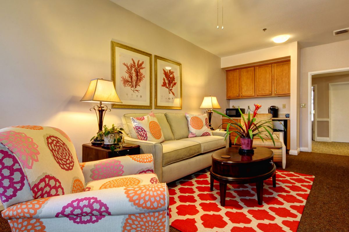 A vibrant living room with colorful decor and artwork, featuring a sofa, coffee table, and lamps.