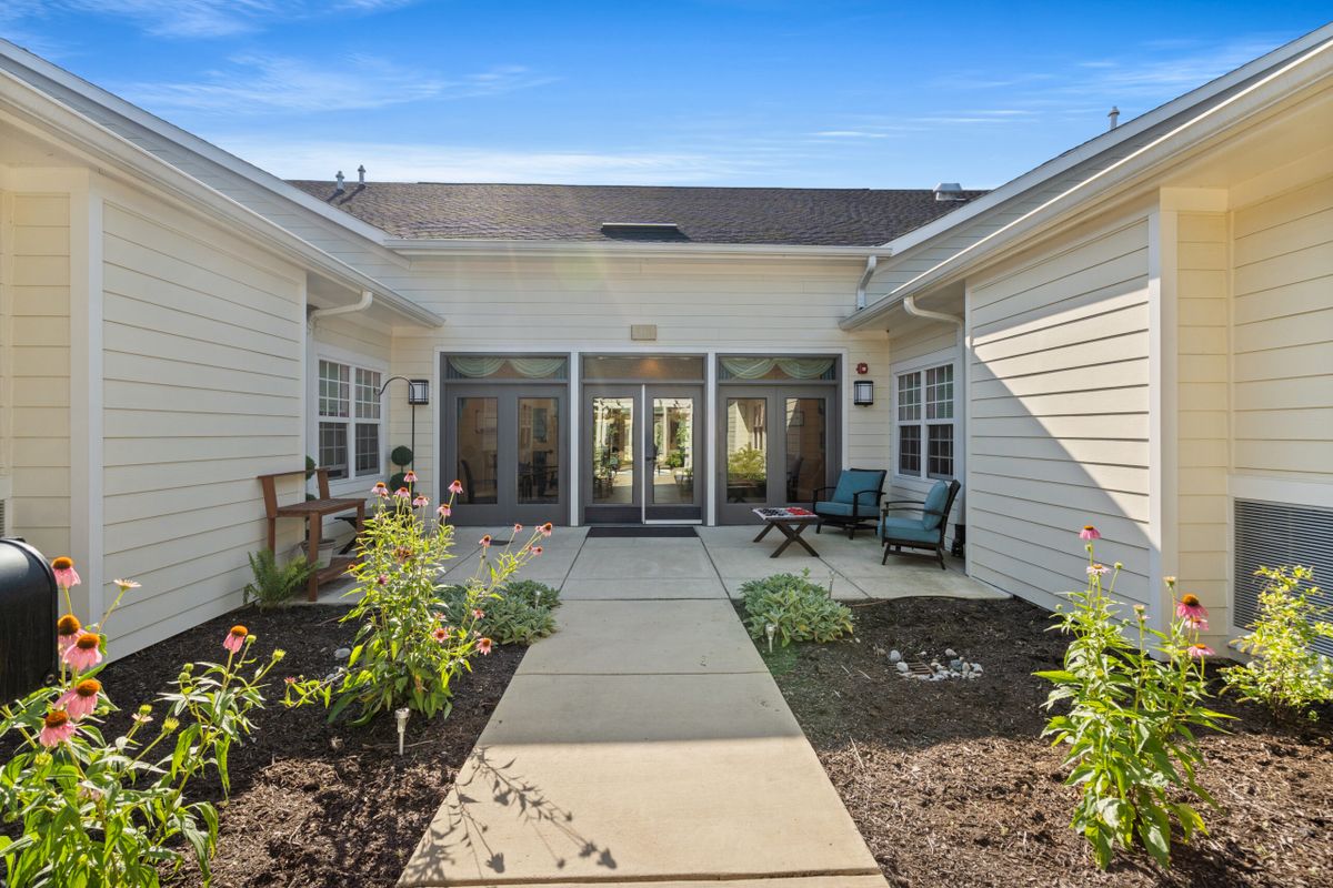 A serene courtyard with outdoor seating and a garden, surrounded by a residential building.