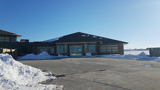 A modern building surrounded by snow, under a clear blue sky.