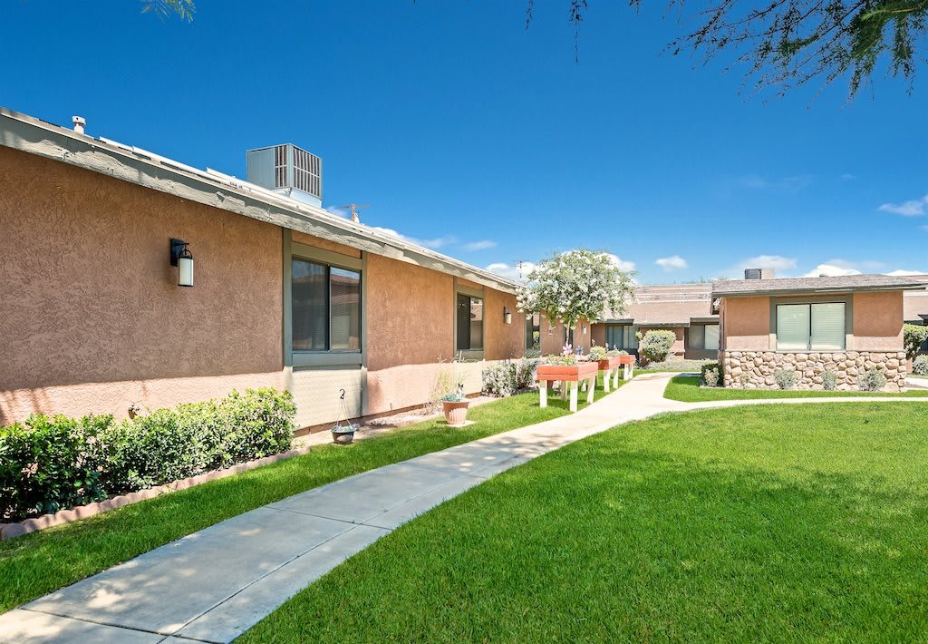 A well-maintained residential area with a green lawn and a pathway.