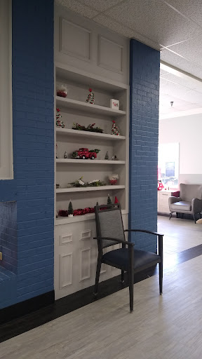 A cozy corner showcasing a neatly arranged shelf against a blue wall, complemented by a simple chair.
