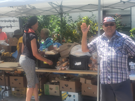 A vibrant community market scene with a vendor happily engaging with customers.