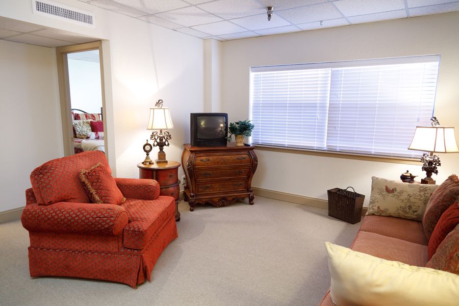 A cozy living room with an armchair, TV, lamp, and window.