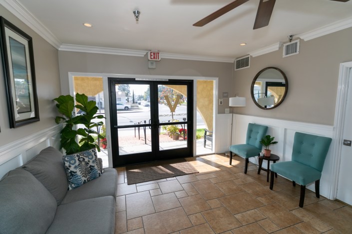A cozy lobby area with seating, plants, and a mirror near the entrance.