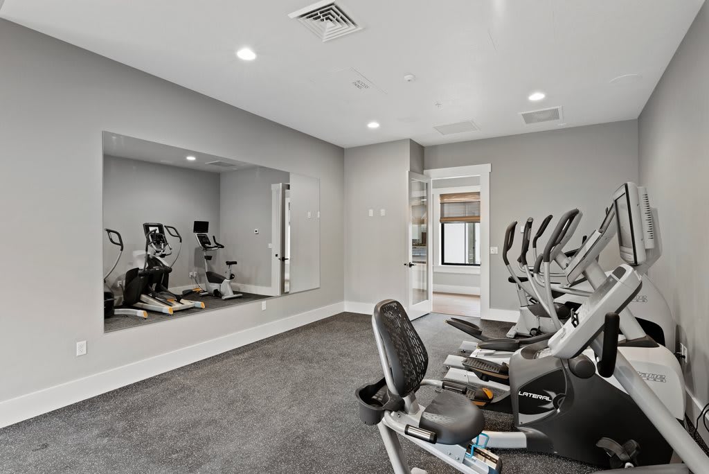 A modern gym featuring exercise machines and a large mirror.