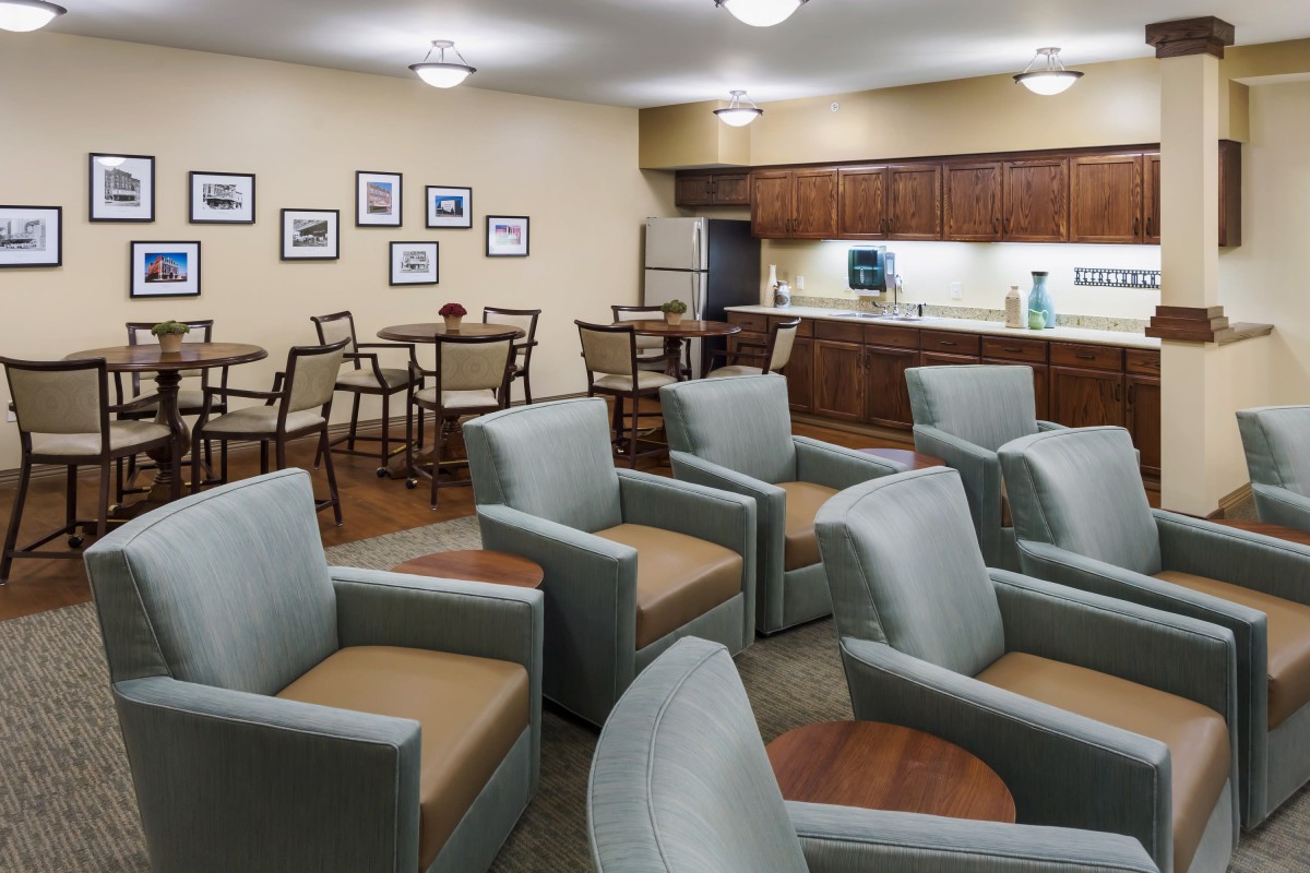 An inviting waiting room with comfortable seating and tables, featuring warm lighting and decorative elements.