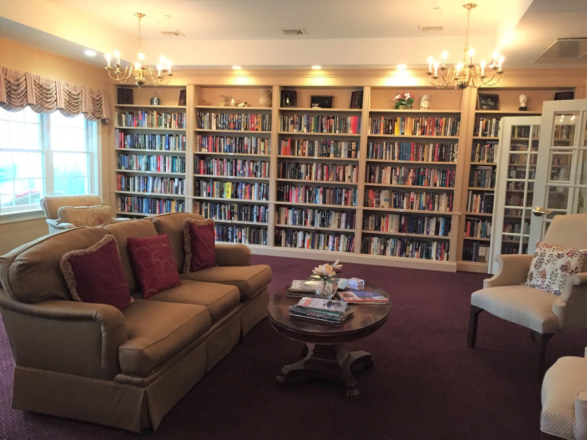 A cozy library room with shelves full of books, a comfortable sofa, and a coffee table.
