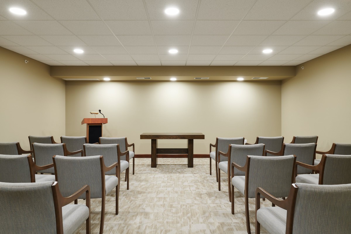 An empty conference room with rows of chairs facing a podium.