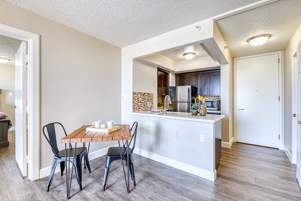 A modern kitchen and dining area in an apartment featuring a wooden table with chairs and a view into the kitchen space.