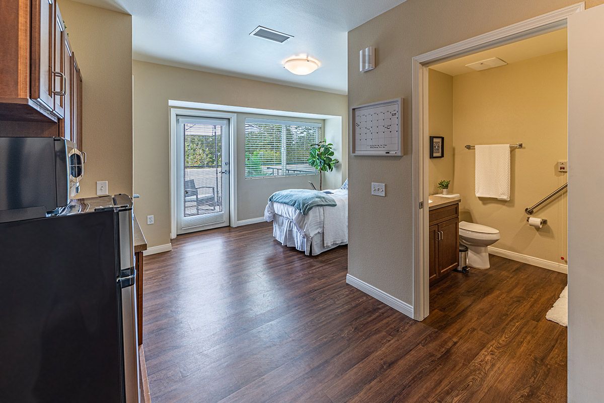 A modern, minimalist bedroom with hardwood floors and large windows allowing ample natural light.
