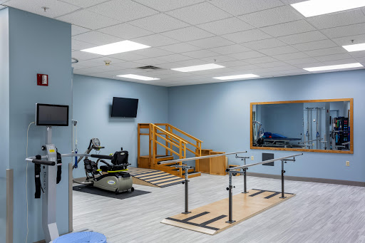 A well-equipped physical therapy room featuring exercise bars, a staircase for rehabilitation exercises, and various therapeutic equipment.