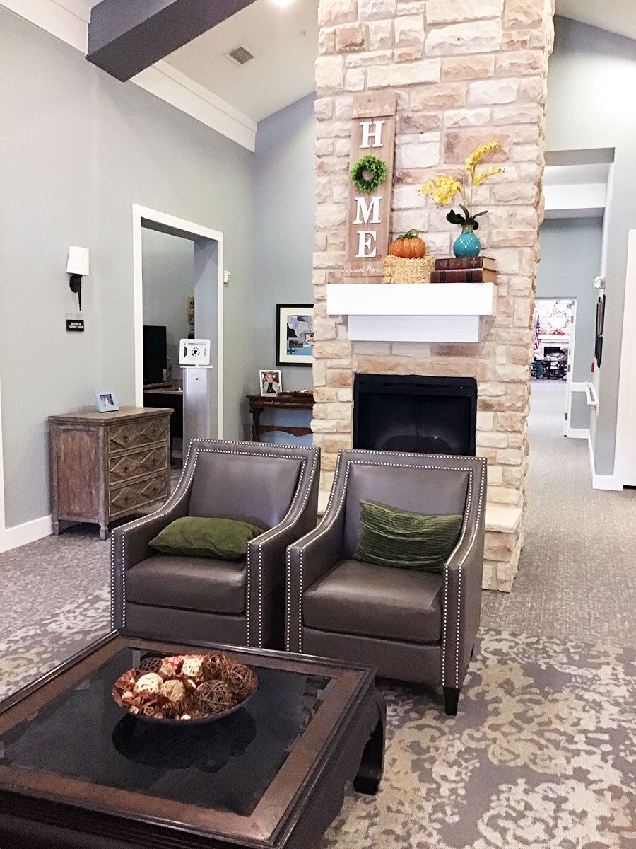 A cozy living room featuring comfortable armchairs, a stone fireplace, and tasteful home decor.