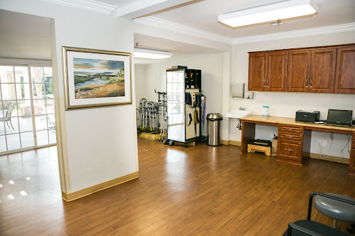 A spacious interior view of a kitchen area featuring wooden flooring and artwork on the wall.