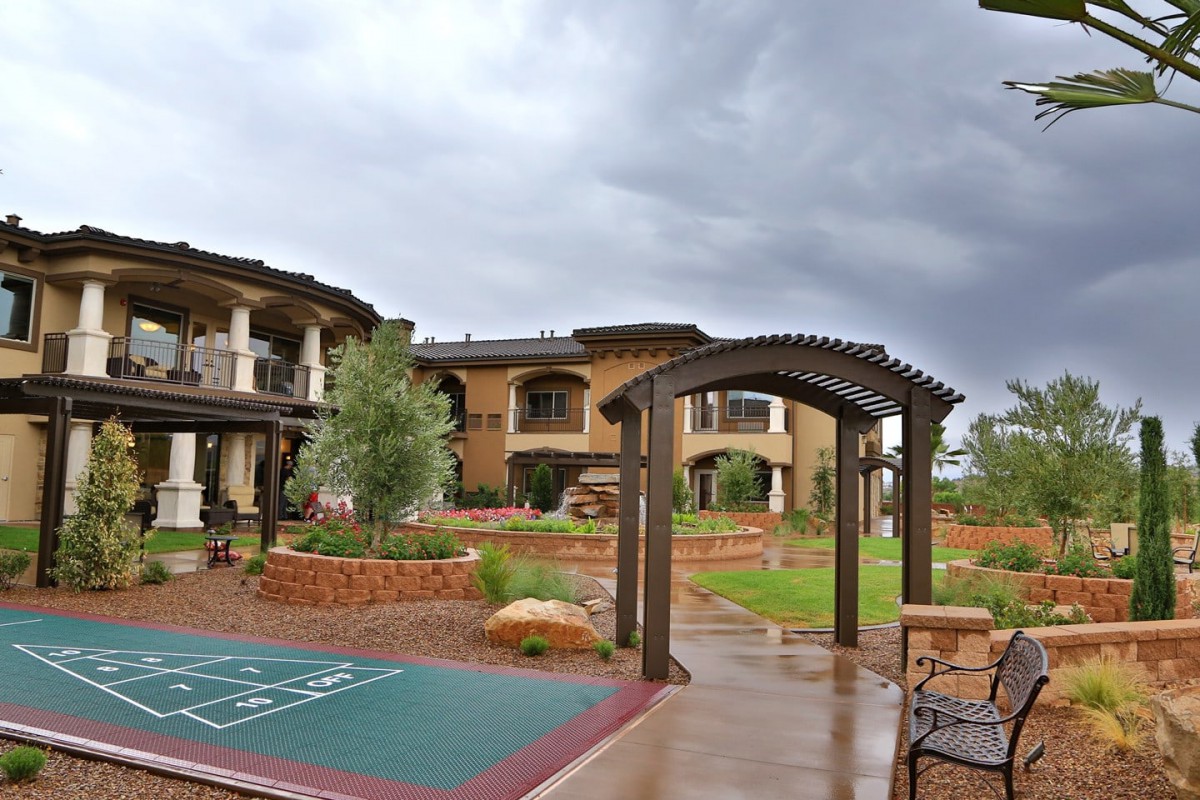 A scenic courtyard with a pathway and garden set against a building under a stormy sky.