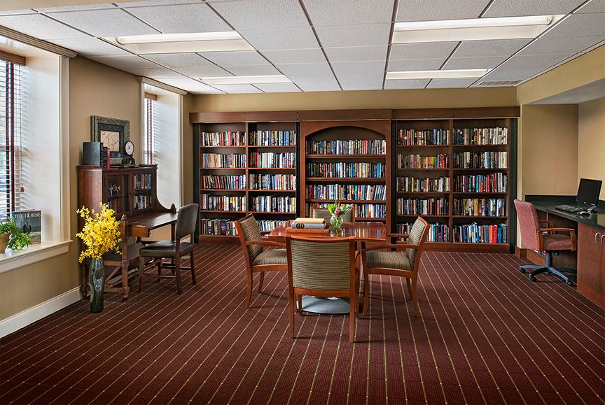 A quiet library reading room with bookshelves, a table, and chairs.