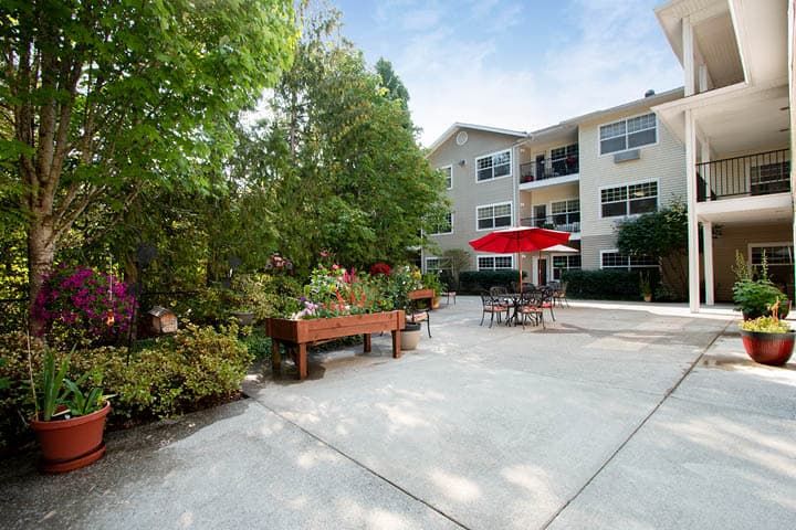A view of an apartment complex patio area with garden planters and outdoor seating.