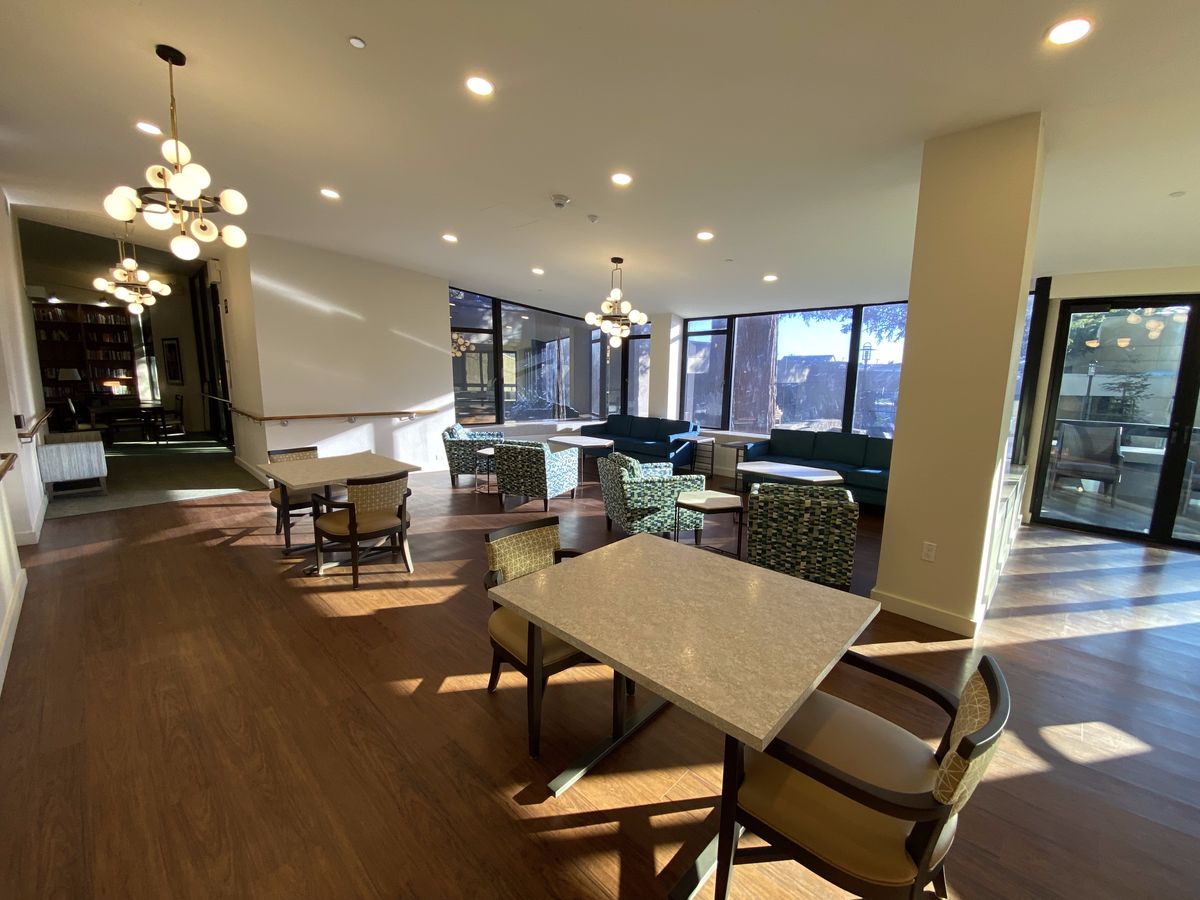 A modern dining area with elegant lighting, comfortable seating, and large windows.