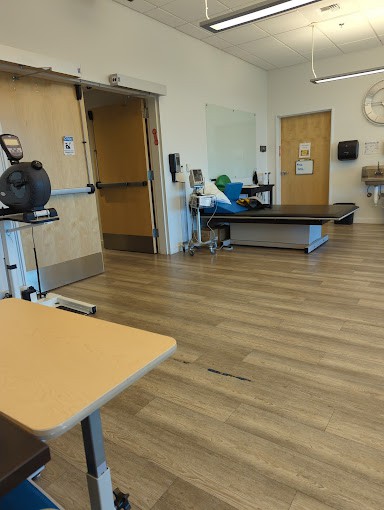 A therapy room equipped with exercise machines and a treatment table.