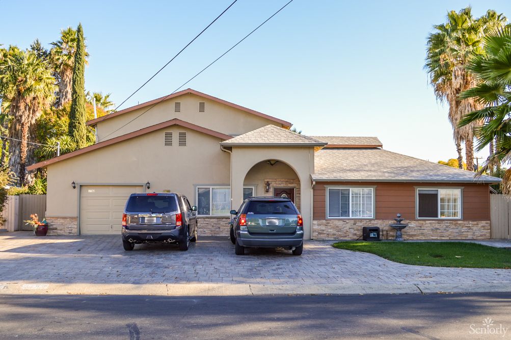 A suburban house with two cars parked in the driveway.