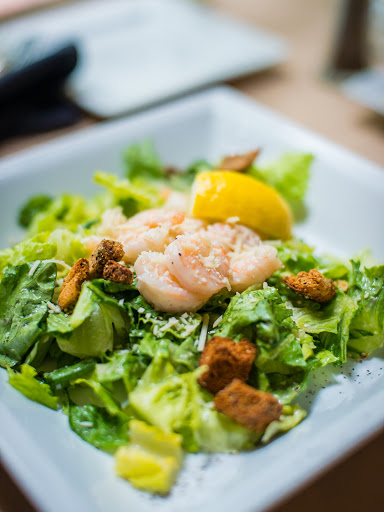 A refreshing shrimp salad featuring crisp lettuce, crunchy croutons, and a slice of lemon.
