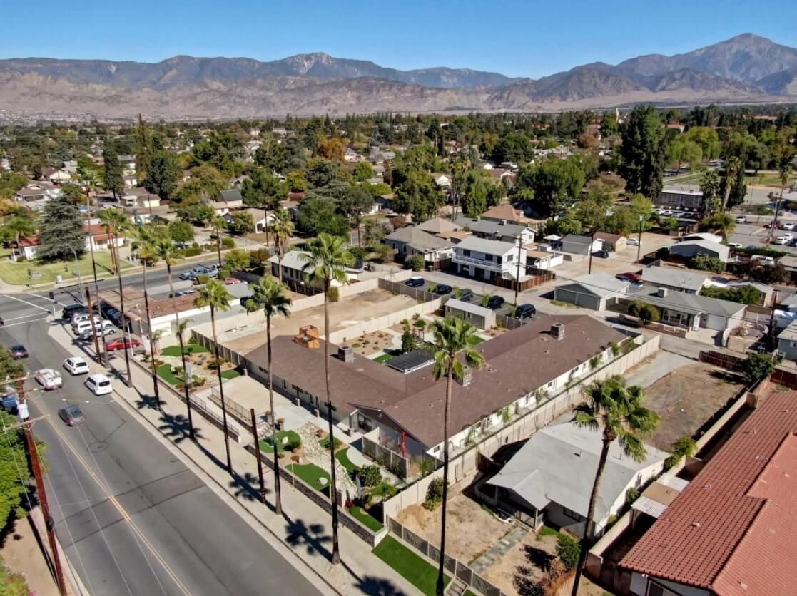 Aerial view of a residential neighborhood with palm trees and mountains in the background.
