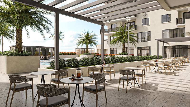 A modern outdoor patio with tables and chairs overlooking a pool area with palm trees.