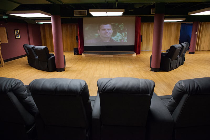 A cozy home theater setup with leather chairs facing a large projector screen.