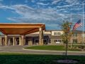A modern building with a large entrance and a spacious surrounding landscape under a partly cloudy sky.