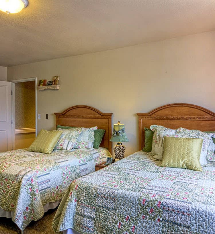 A cozy bedroom with two neatly made beds and decorative pillows.