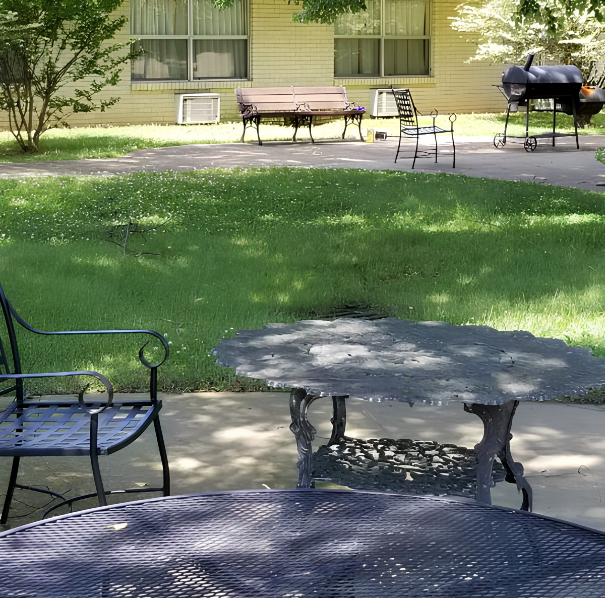 A peaceful garden setting with patio furniture and lush greenery.