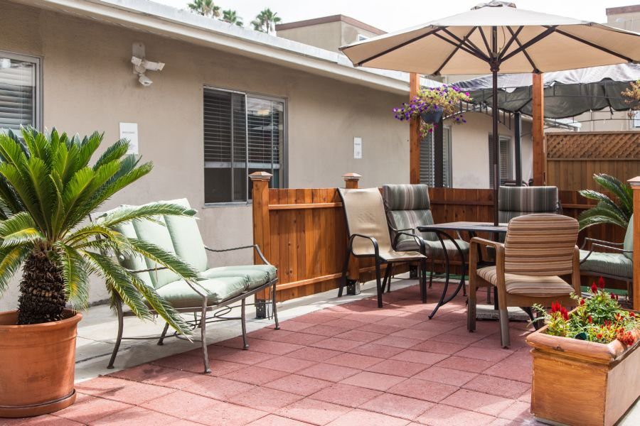A cozy outdoor patio area with various chairs, a table, and an umbrella.