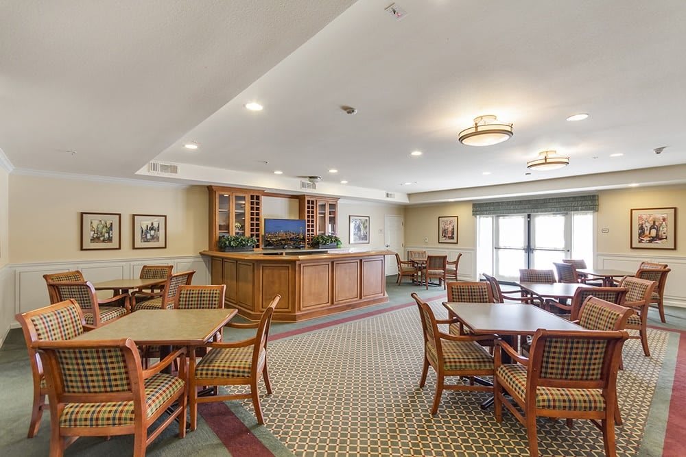 A cozy dining area with wooden tables and chairs, featuring a bar counter in a well-lit space.