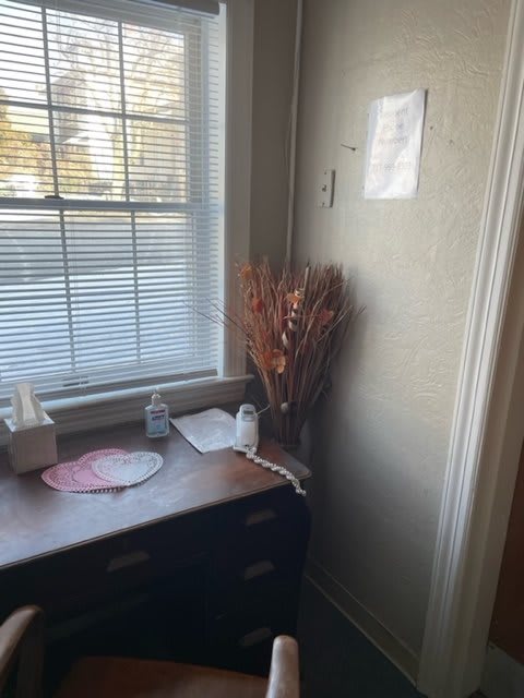 A cozy corner with a small desk by the window, featuring dried flowers and office essentials.