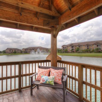 A cozy gazebo overlooking a tranquil lake in a residential area offers a perfect spot for relaxation.