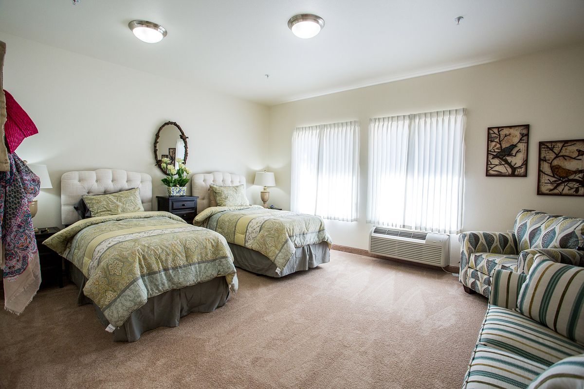 A cozy bedroom featuring twin beds with a large window letting in natural light.