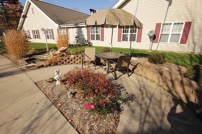 A sunny patio with outdoor furniture, an umbrella, and a small garden area.