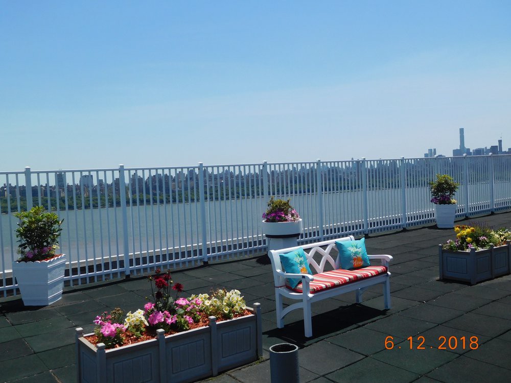 A rooftop garden with a bench and colorful flowers overlooking the city skyline.
