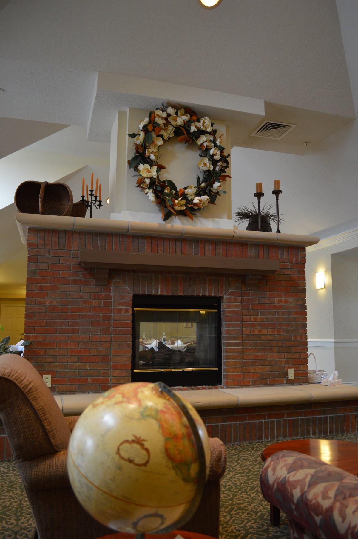 A cozy brick fireplace decorated with a wreath and candles, creating a warm and inviting atmosphere.