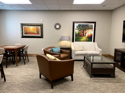 A cozy living room setup with a white sofa, brown armchairs, and decorative artwork on the walls.