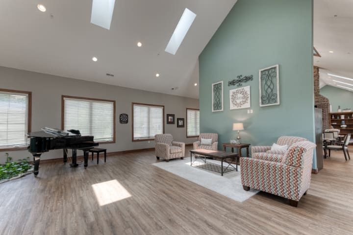 A spacious living room with modern furnishings, highlighted by skylights and a hardwood floor.