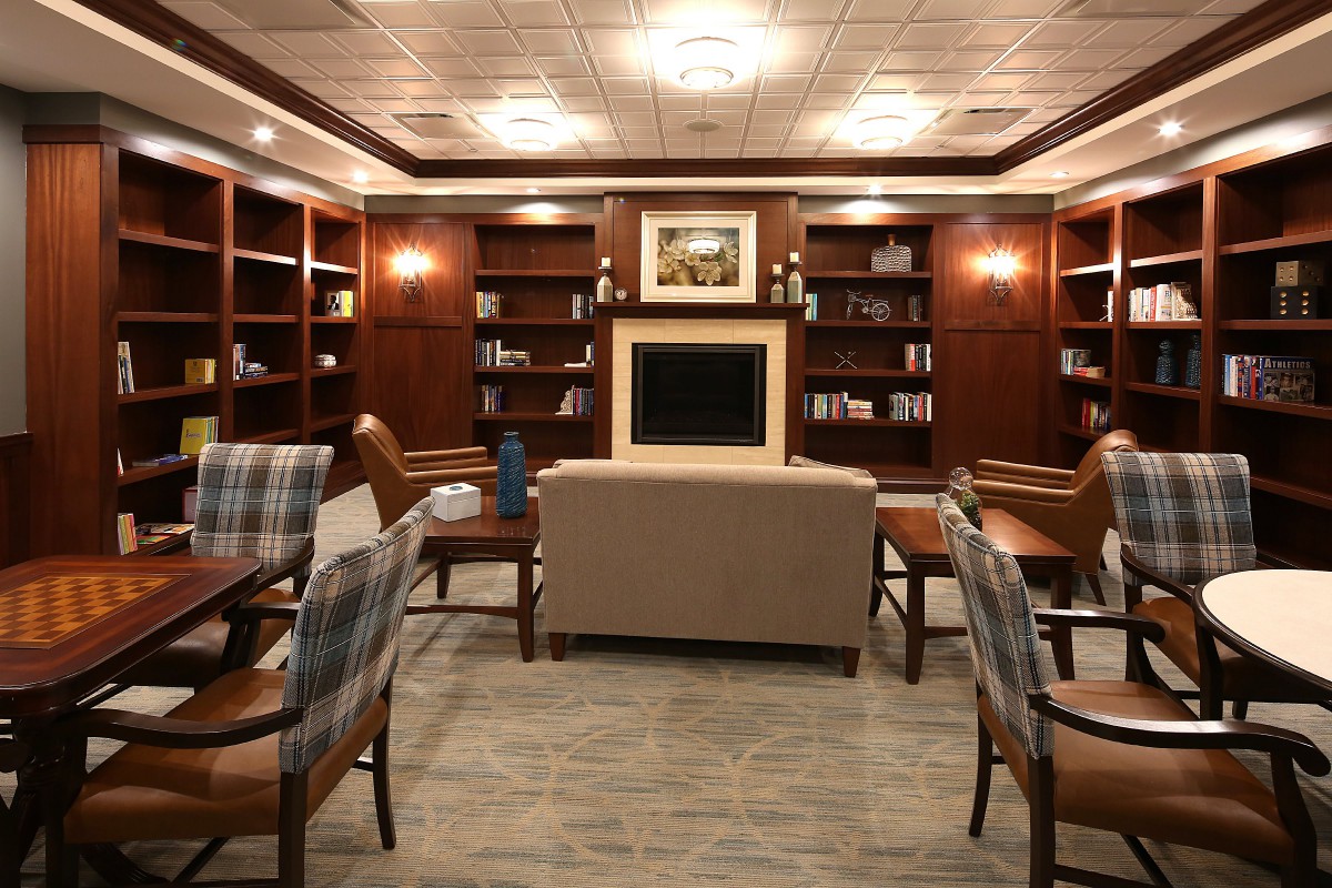 A cozy library reading room featuring comfortable seating, wooden bookshelves, and a warm ambiance.