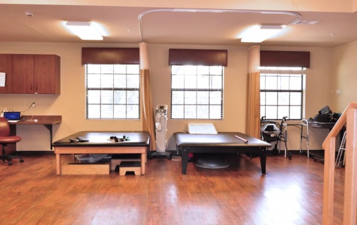 A spacious physical therapy room with treatment tables and exercise equipment.