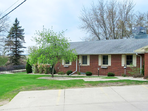 A charming brick residence surrounded by greenery, featuring a well-maintained driveway.