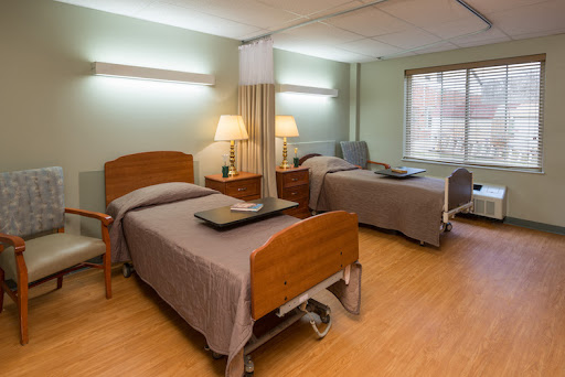 A well-lit patient room in a hospital featuring two adjustable beds and warm, inviting decor.