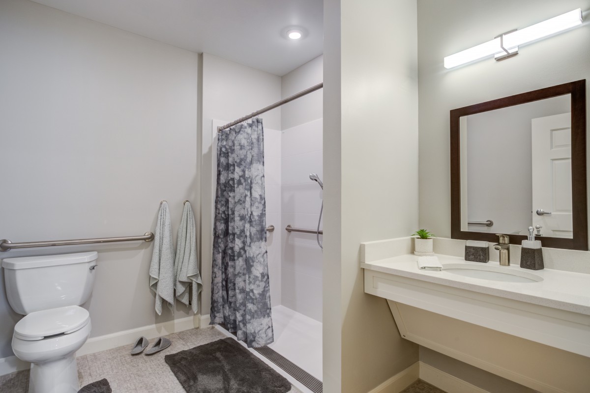 A modern bathroom with a shower area, towels, and a sink with a mirror.