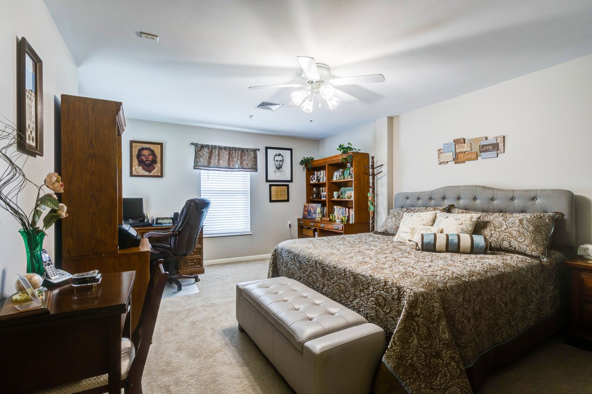 A cozy bedroom with a bed, desk, and bookshelf.