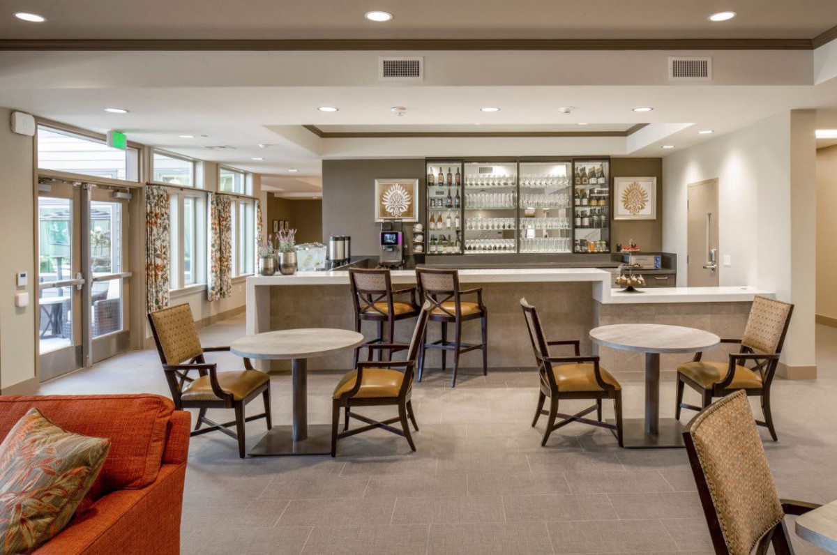 A modern lounge with bar seating and tables, featuring comfortable chairs and inviting decor.