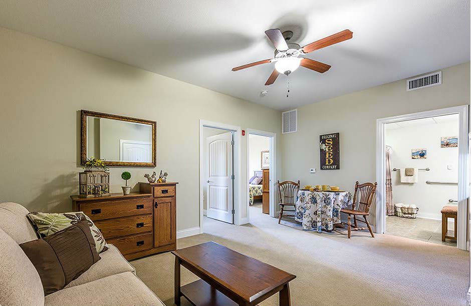 A cozy living room with comfortable seating, a wooden table, and a ceiling fan overhead.