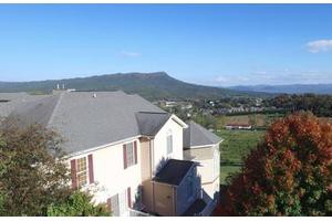 A house overlooking a scenic mountainous landscape under a clear blue sky.