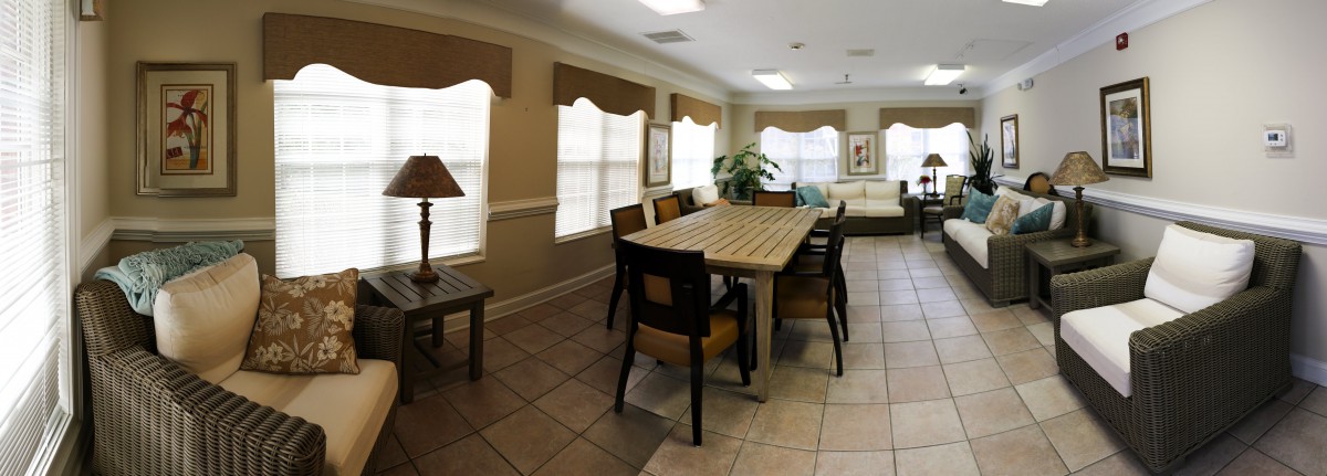 A well-lit dining area with a wooden table and chairs surrounded by windows.